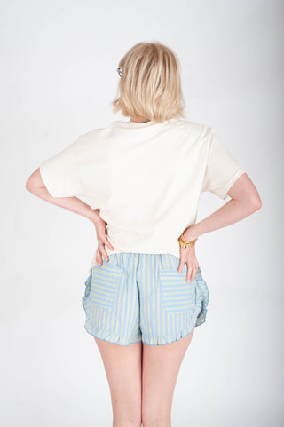 Woman wearing a white top and light blue striped shorts on a white background