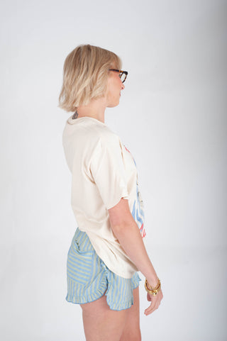 Woman wearing a white t-shirt and light blue shorts on a plain background