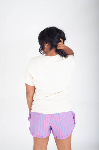 Person wearing a white t-shirt and purple striped shorts on a white background
