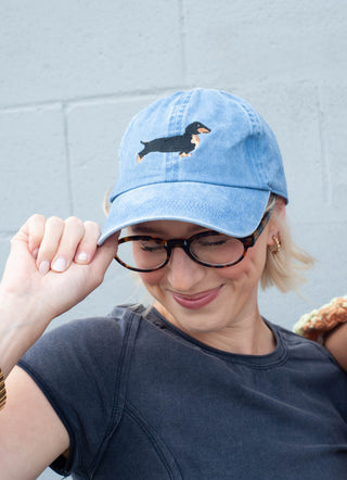 Person wearing a blue cap with a dog design against a gray wall