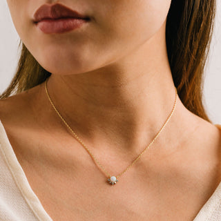 a person wearing a gold necklace with a charm on it