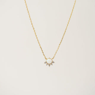 a gold necklace with a crystal fan charm