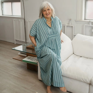 Woman wearing a teal striped pajama set in a modern living room.