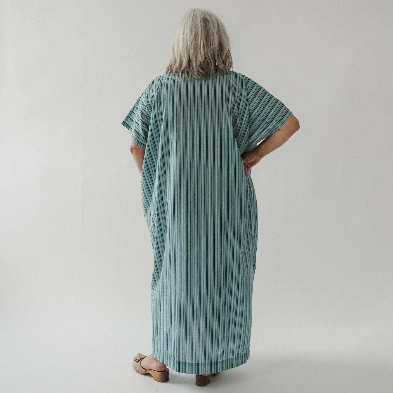 Person wearing a green striped dress against a plain background