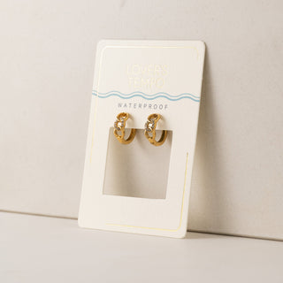 Gold hoop earrings on a branded card against a neutral background