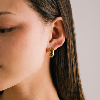 women wearing a gold textured hoop earring