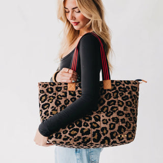 women wearing a leopard tote bag against a neutral photo background.