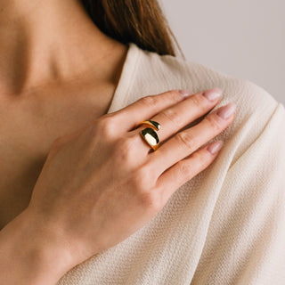 A person wearing a gold-colored ring on their finger, with the ring prominently displayed on their hand.