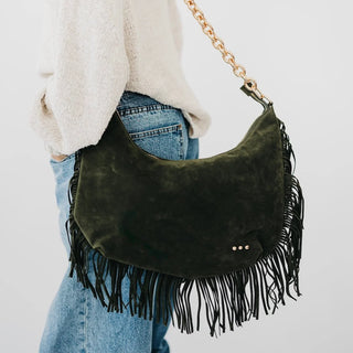 Women carrying a olive fringe shoulder bag against neutral photo background