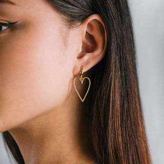 a person wearing large heart shaped earrings 