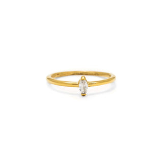 A delicate yellow gold ring featuring a single marquise-cut clear gemstone in a prong setting, centered on a plain white background.