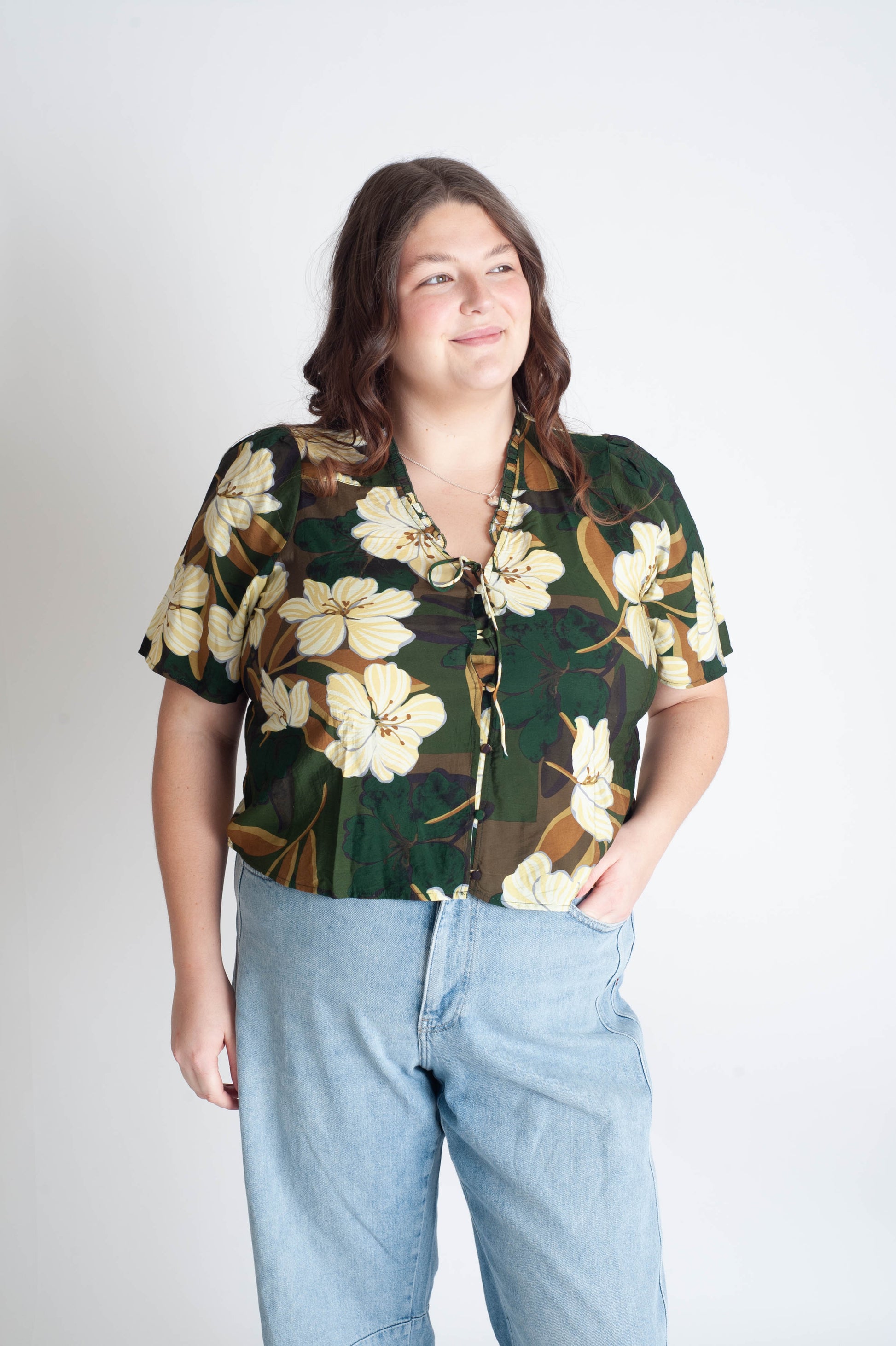 Person wearing a floral blouse and jeans on a plain background
