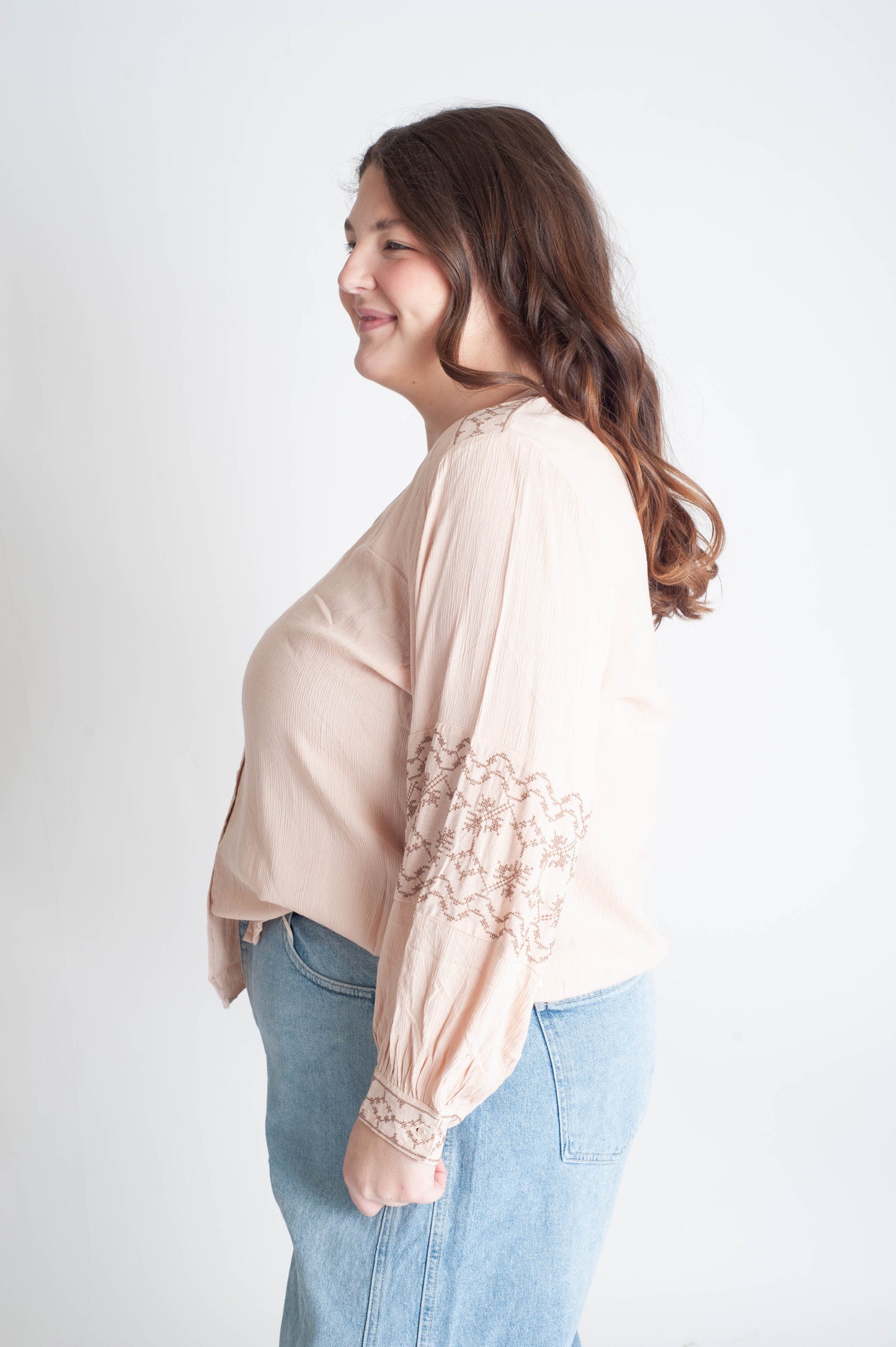Woman wearing a beige blouse with lace details on a white background
