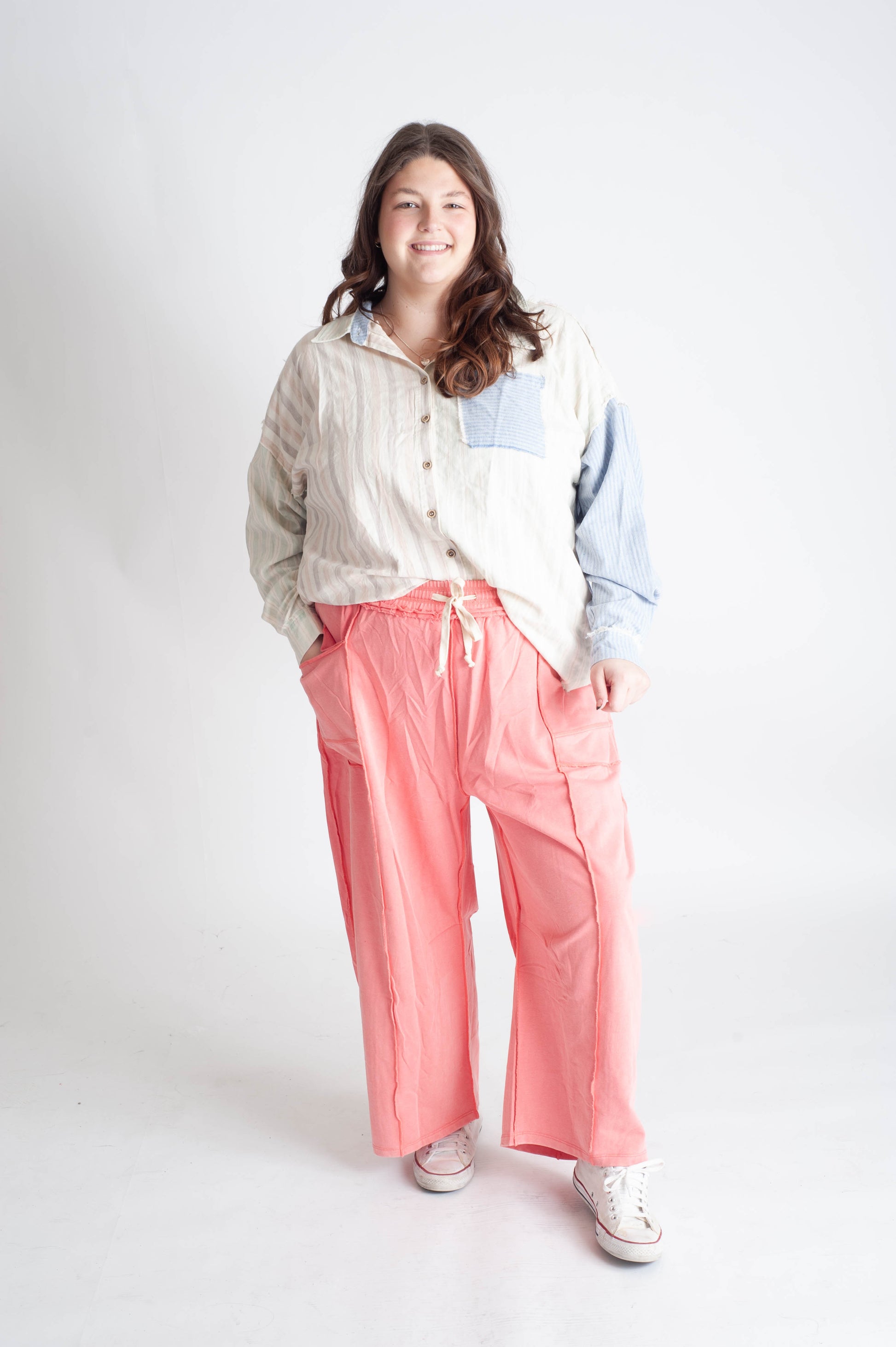 Person wearing a light-colored jacket, white shirt, and pink pants on a white background