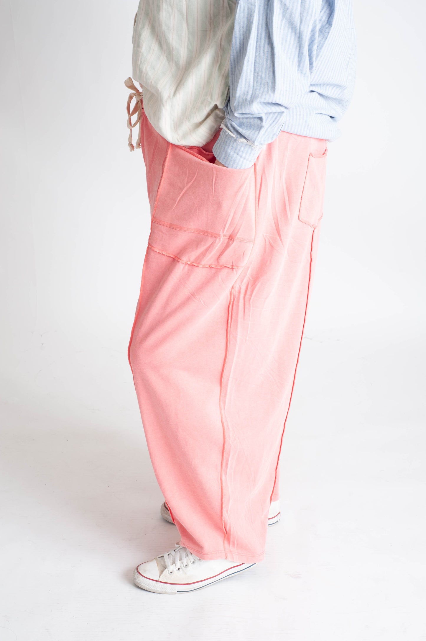 Person wearing light pink pants with a plain background