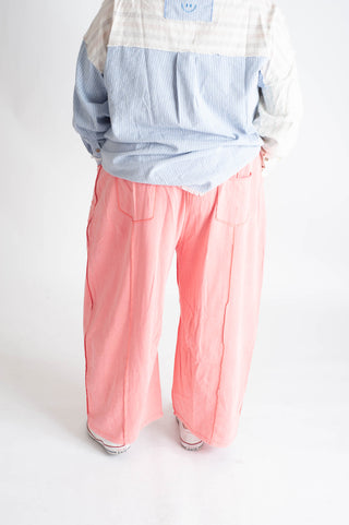 Person wearing a checkered shirt and pink pants on a white background