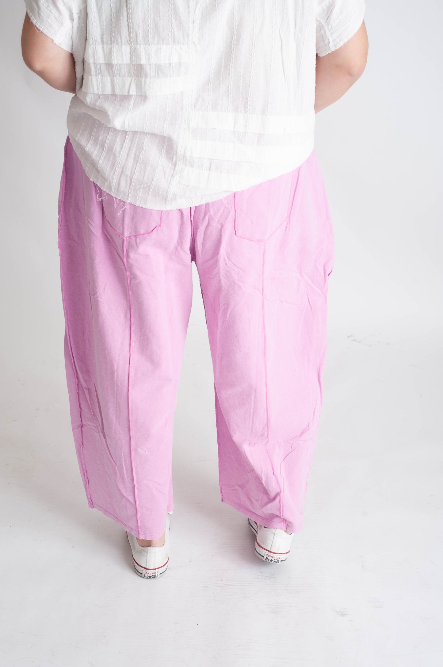 Person wearing a white shirt and pink pants on a plain background