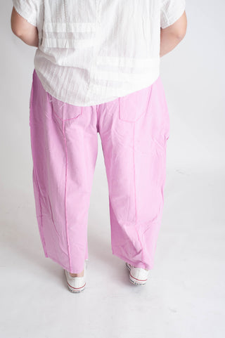 Person wearing a white shirt and pink pants on a plain background