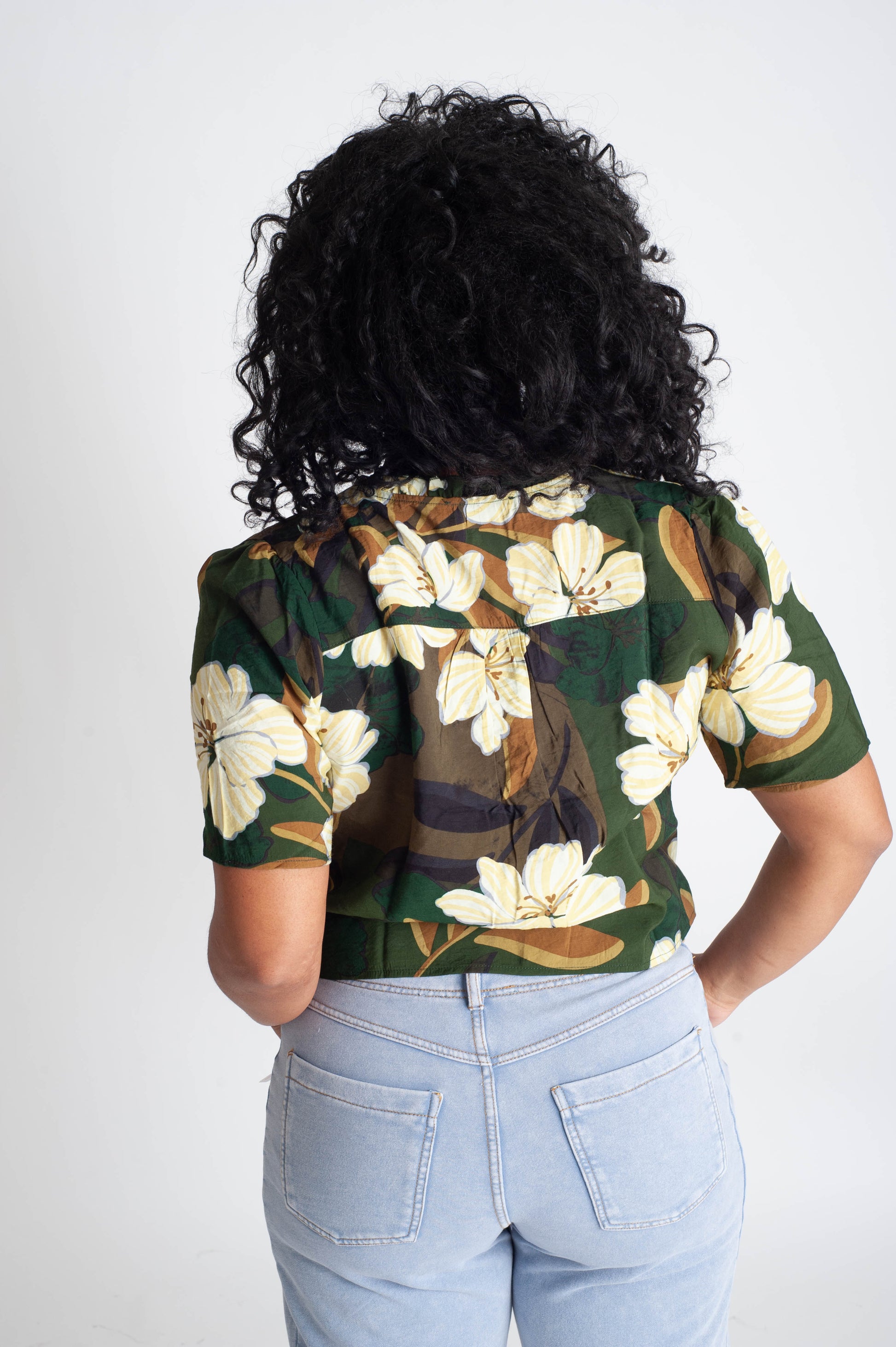 Person wearing a floral patterned shirt with a plain background