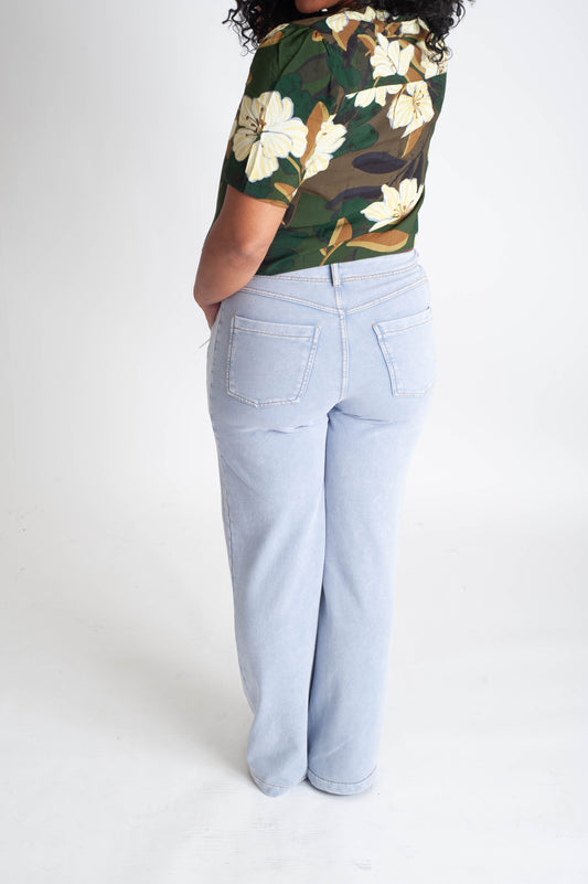 Person wearing a camouflage floral top and light blue jeans on a white background