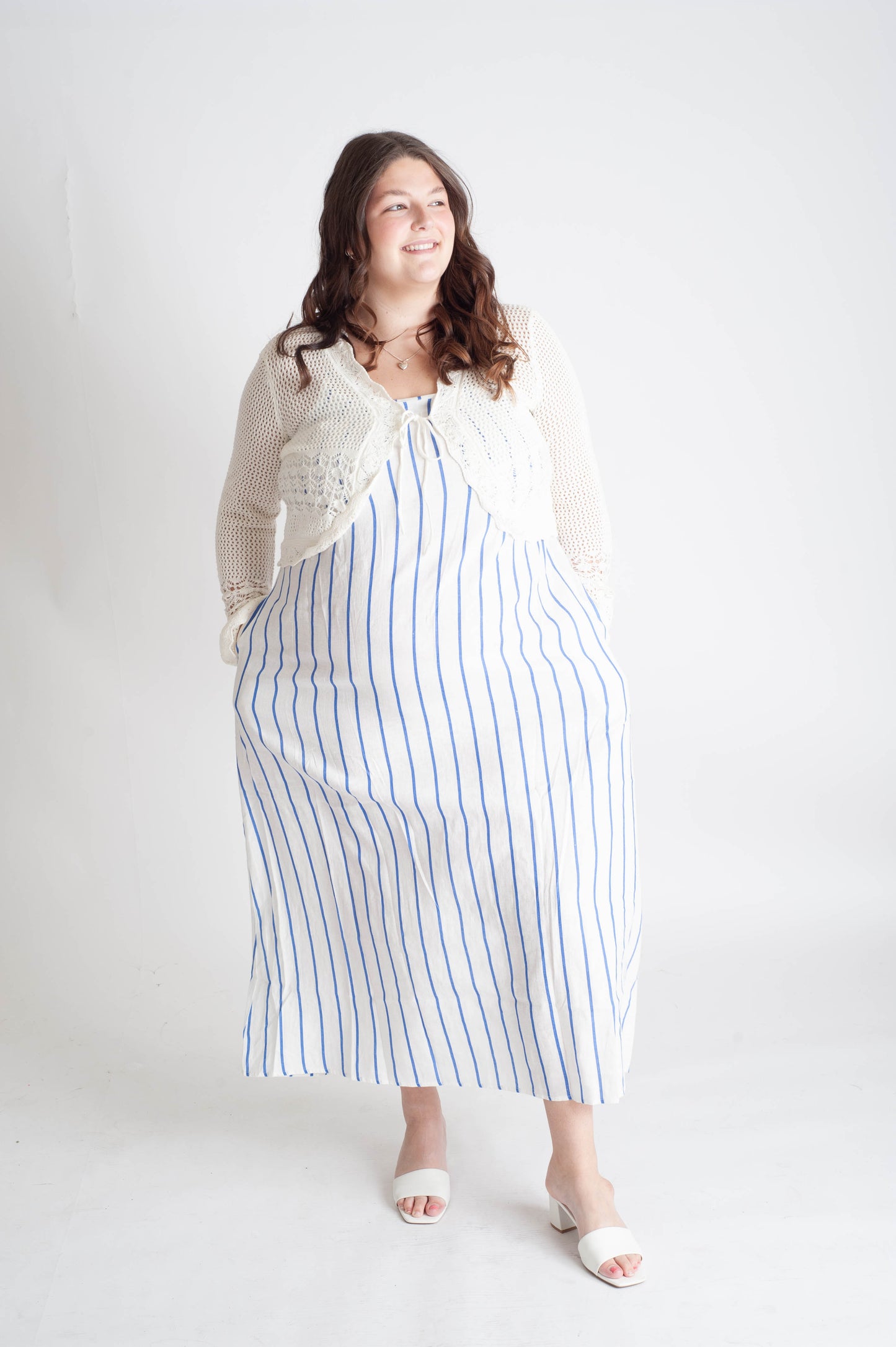 Woman wearing a long white dress with blue stripes against a white background