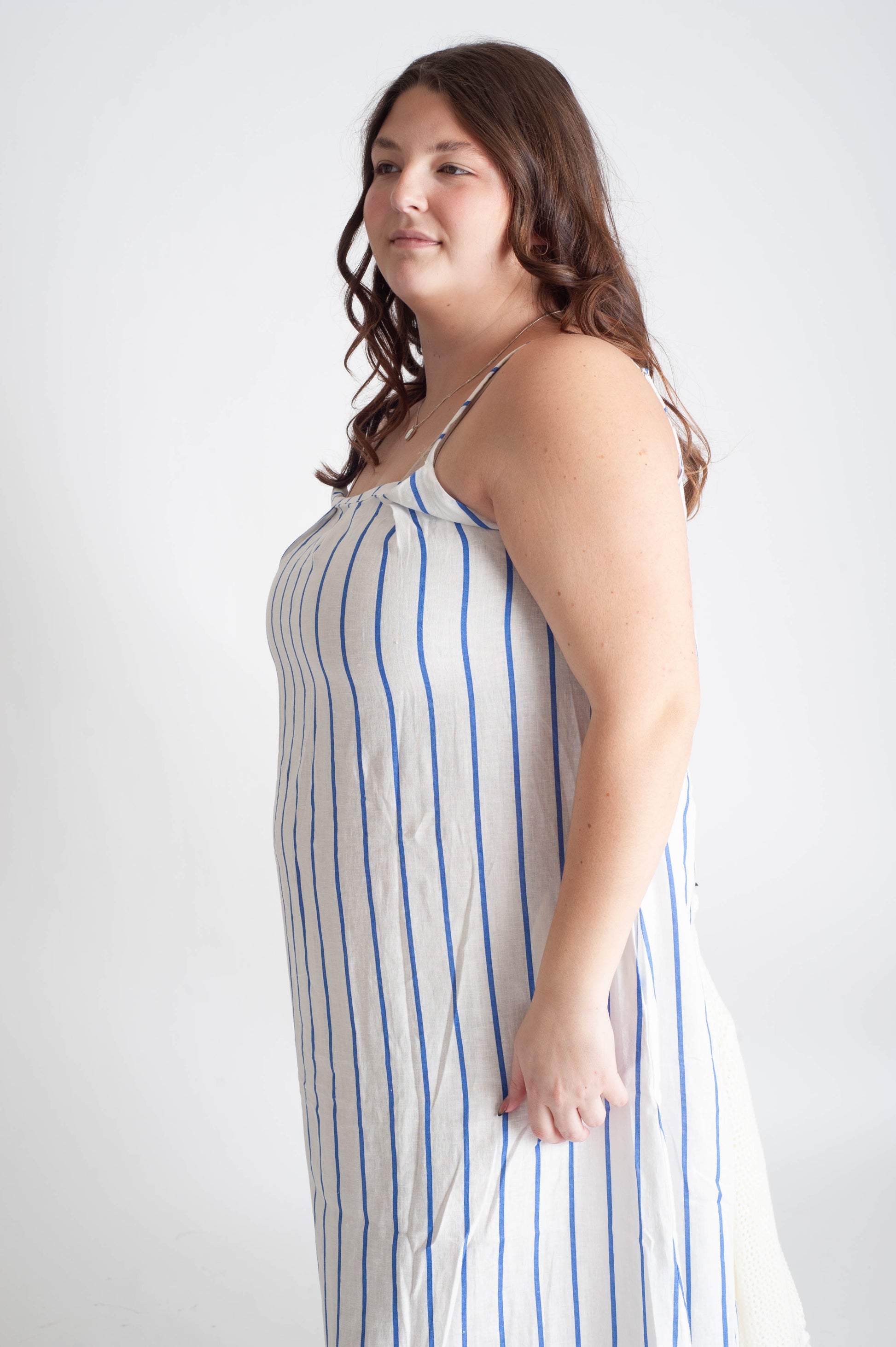 Woman wearing a blue and white striped dress against a plain background
