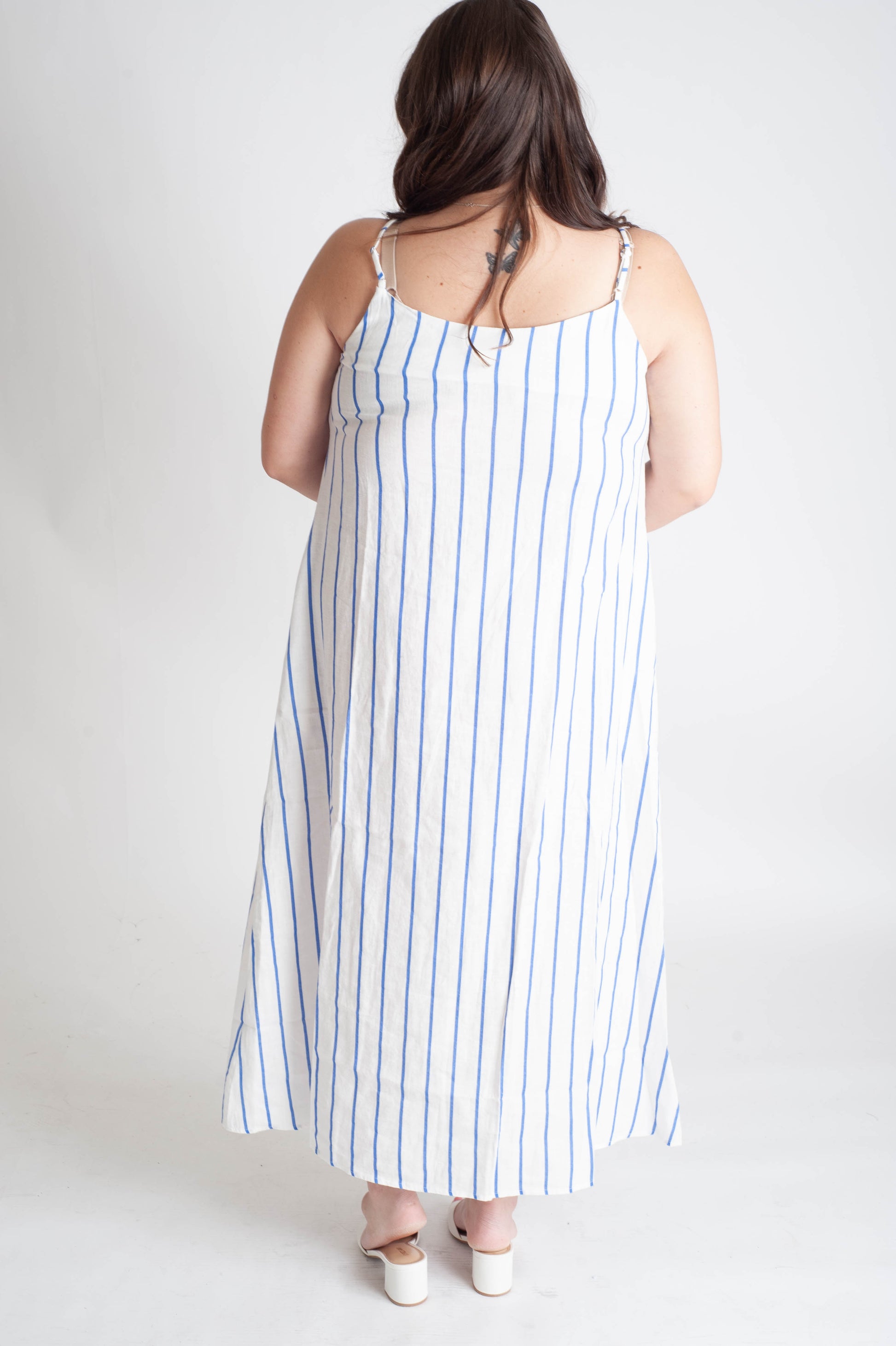 Woman wearing a white dress with blue stripes on a plain background