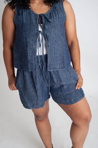 Person wearing a blue denim outfit with a top and shorts on a white background