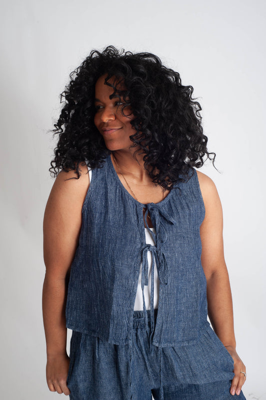 Woman wearing a blue sleeveless top and pants against a plain background