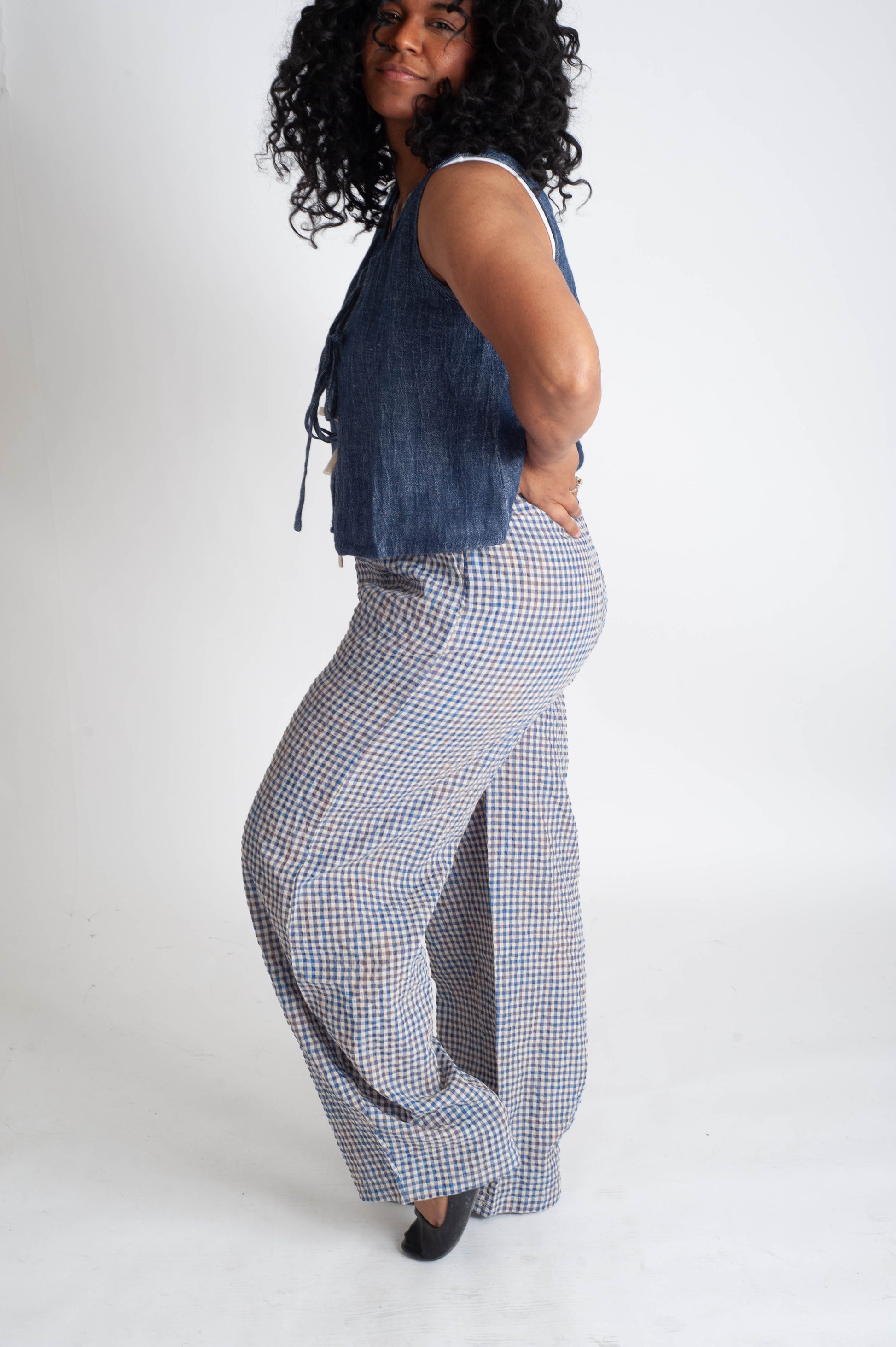 Woman wearing a denim top and checkered pants on a white background