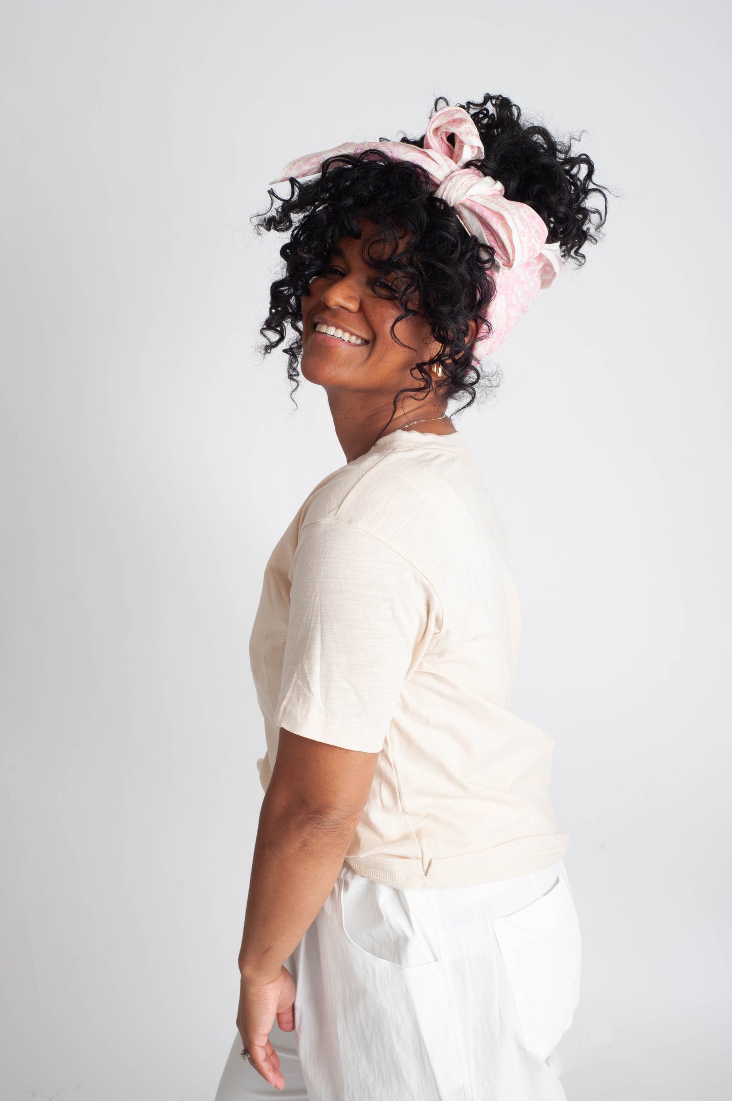 Woman with styled hair wearing a white top against a plain background