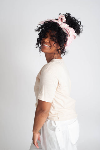 Woman with styled hair wearing a white top against a plain background