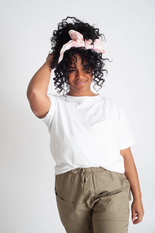 Person wearing a white t-shirt and beige pants with a plain background