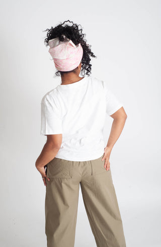 Person wearing a white t-shirt and beige pants with a pink mask on a white background