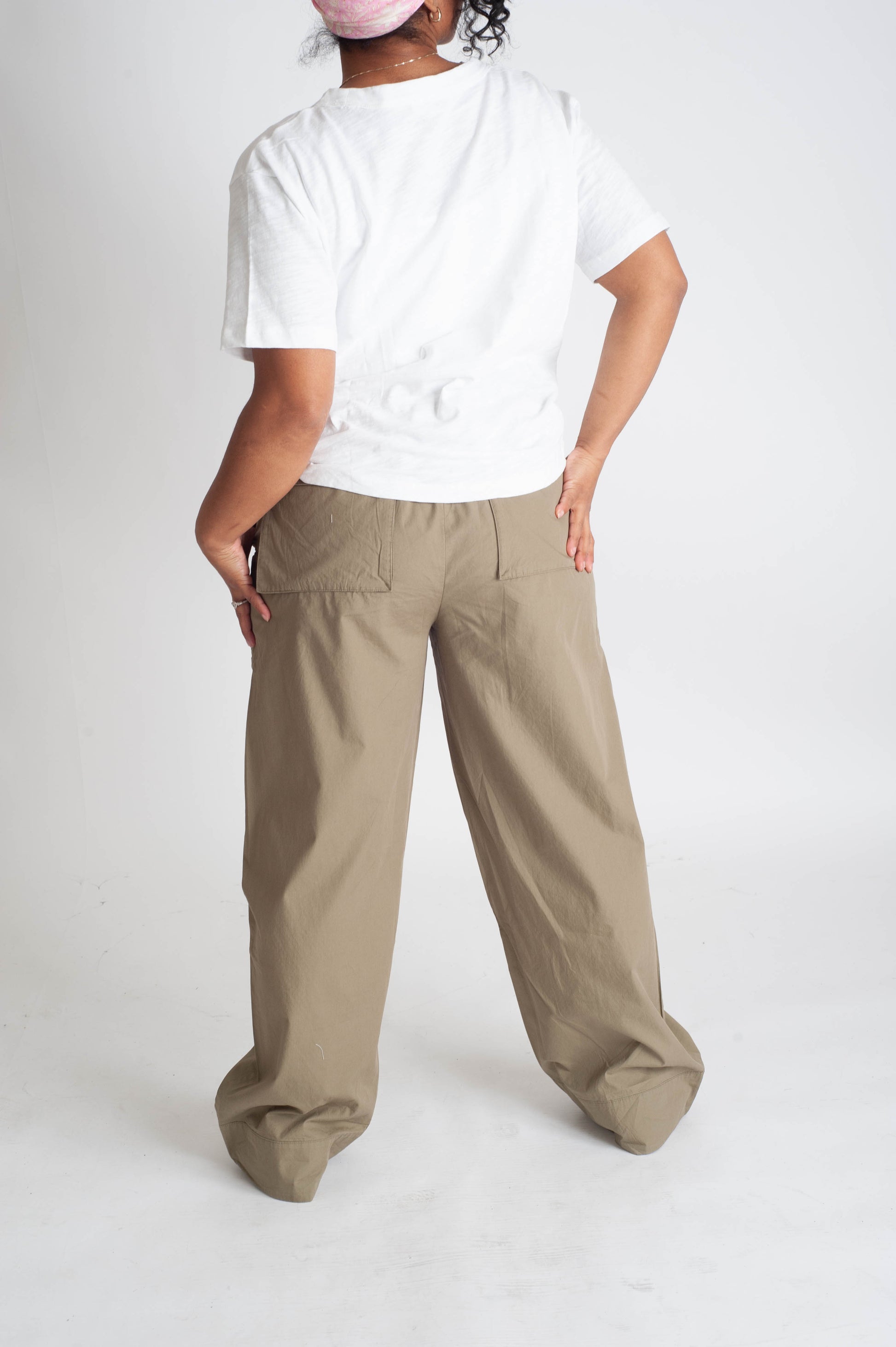 Person wearing a white t-shirt and beige wide-leg pants on a white background