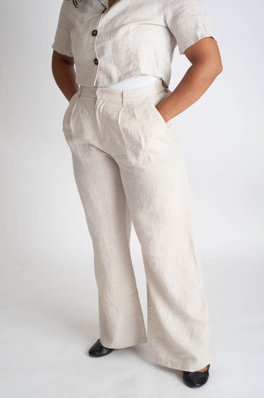 Person wearing a beige outfit with wide-leg pants on a white background