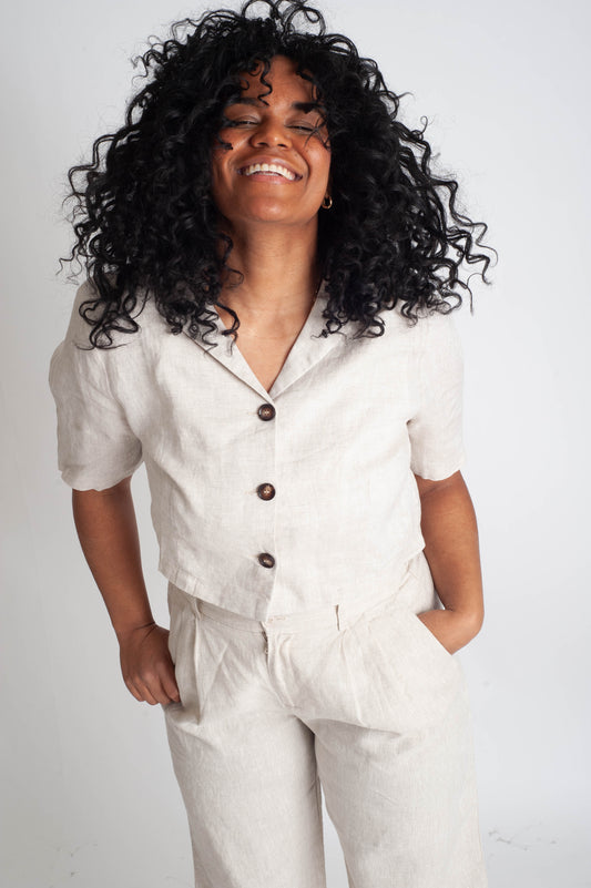 Person wearing a light-colored outfit with buttons on a plain background