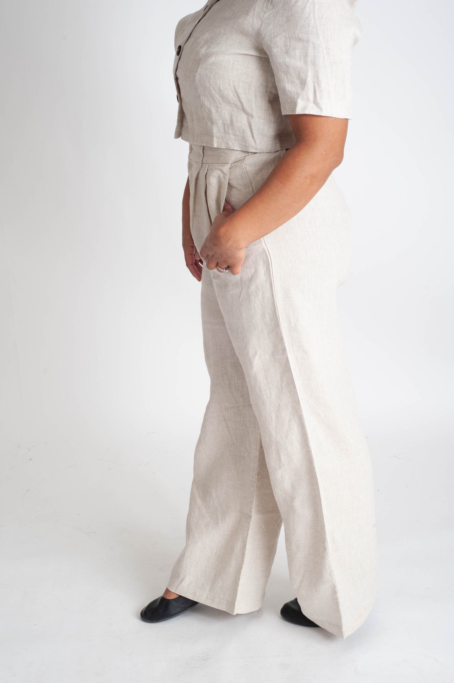 Person wearing a beige outfit with wide-leg pants on a white background