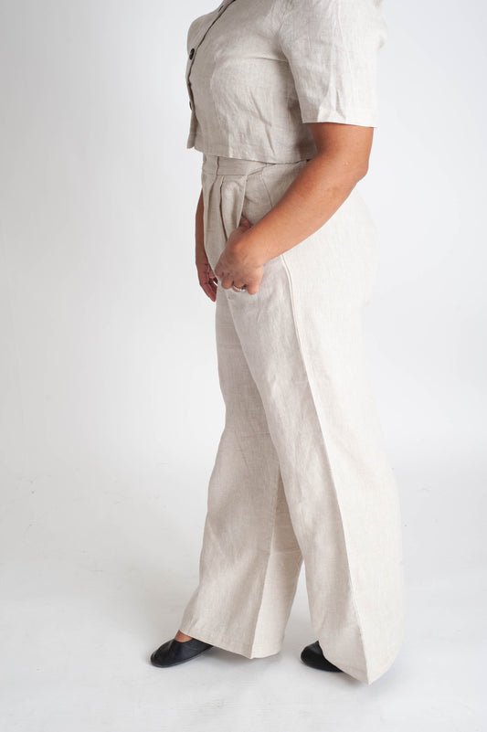 Person wearing a beige outfit with wide-leg pants on a white background
