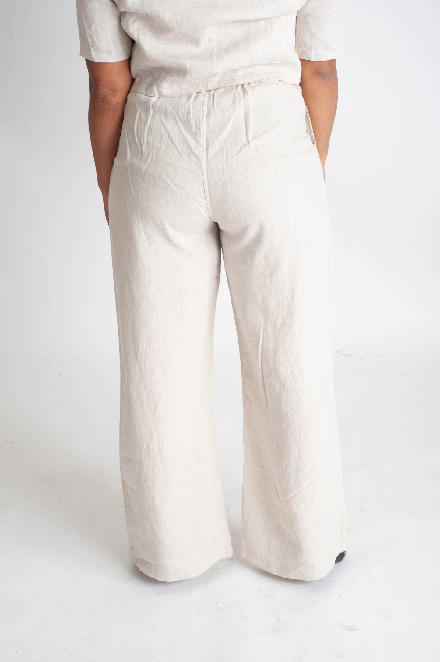 Person wearing beige wide-leg pants on a white background