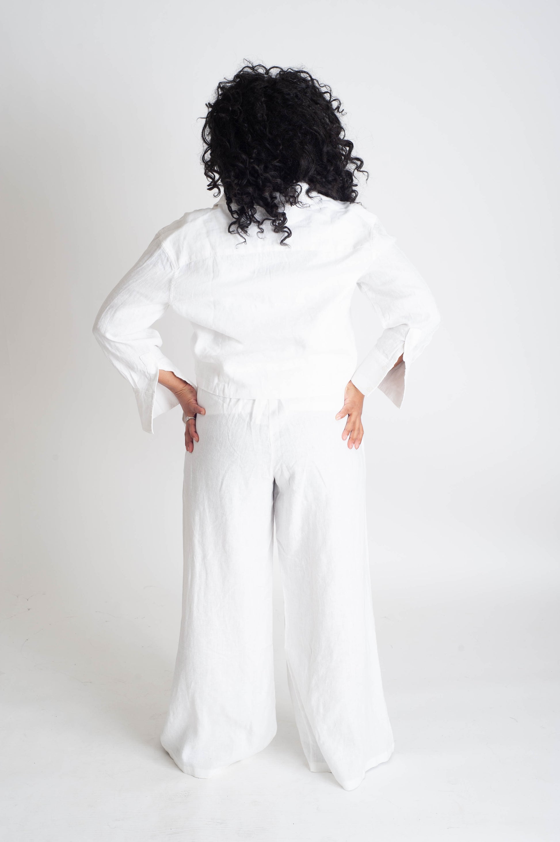 Person wearing a white outfit with wide sleeves on a plain background
