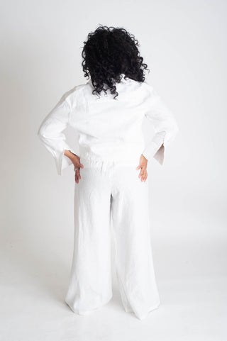 Person wearing a white outfit with wide sleeves on a plain background