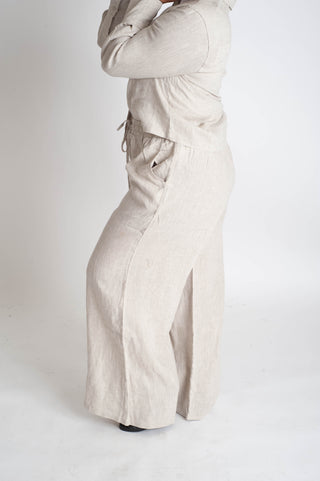 Person wearing a beige top and wide-leg pants on a white background
