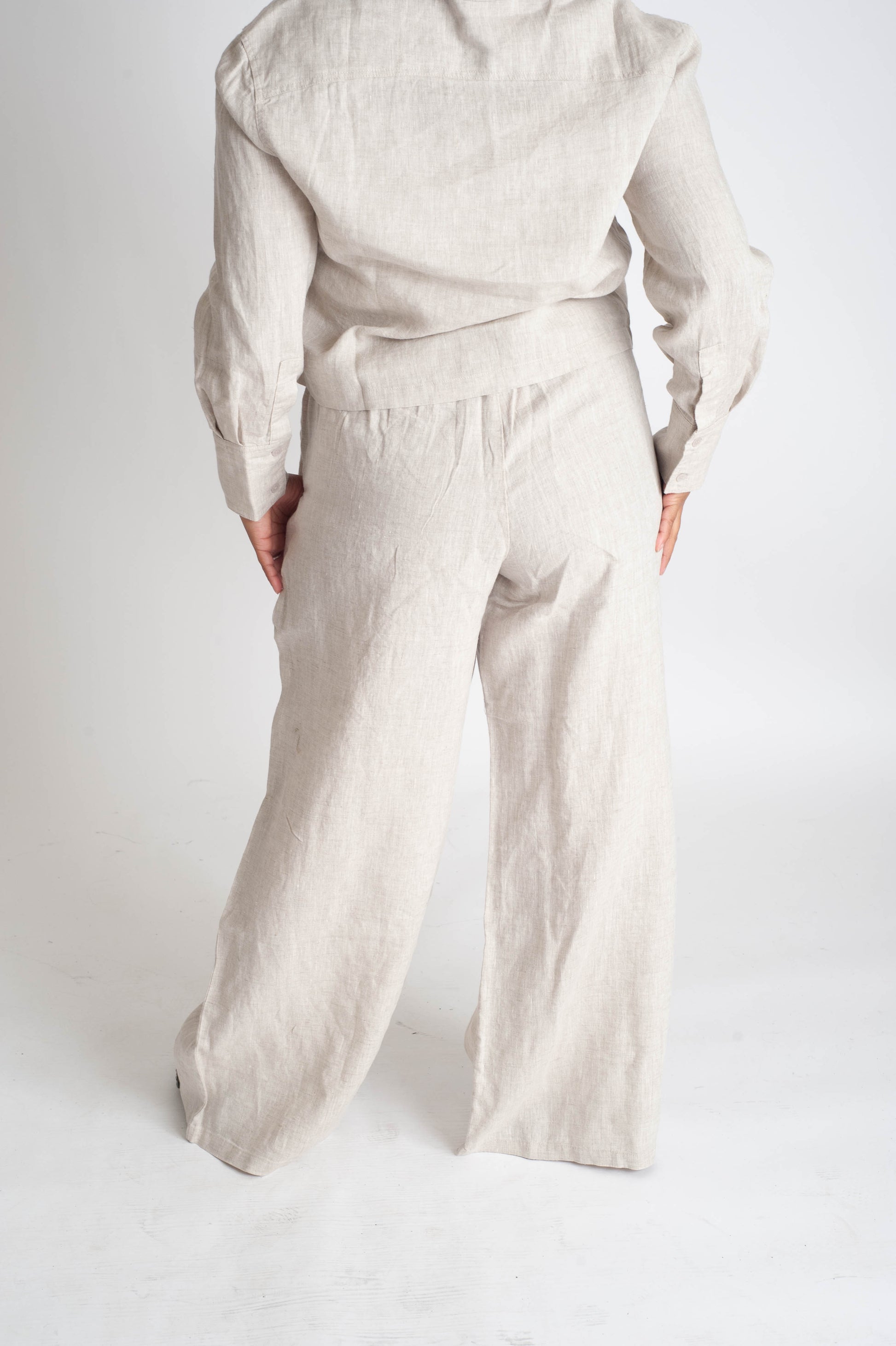 Person wearing a beige outfit with wide-leg pants on a white background