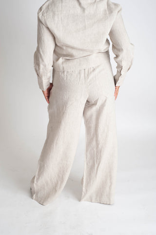 Person wearing a beige outfit with wide-leg pants on a white background