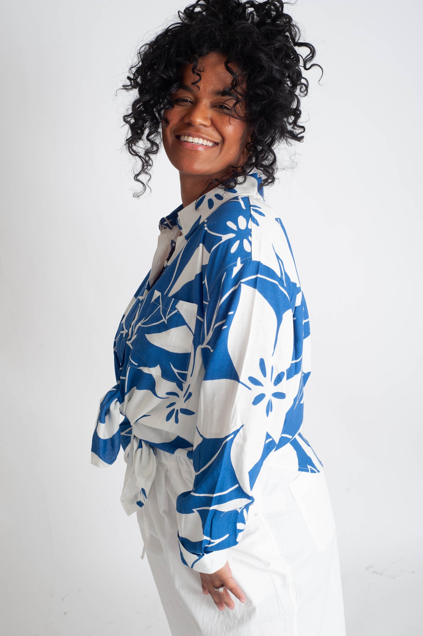 Woman wearing a blue and white floral patterned shirt against a white background