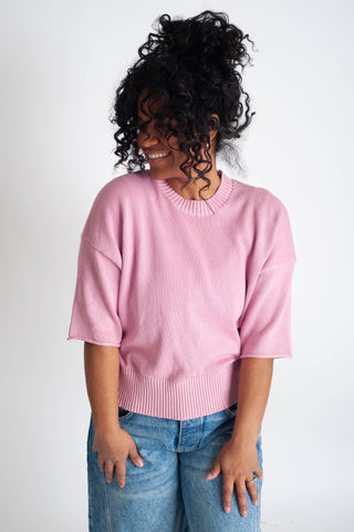 Person wearing a pink sweater and blue jeans on a white background