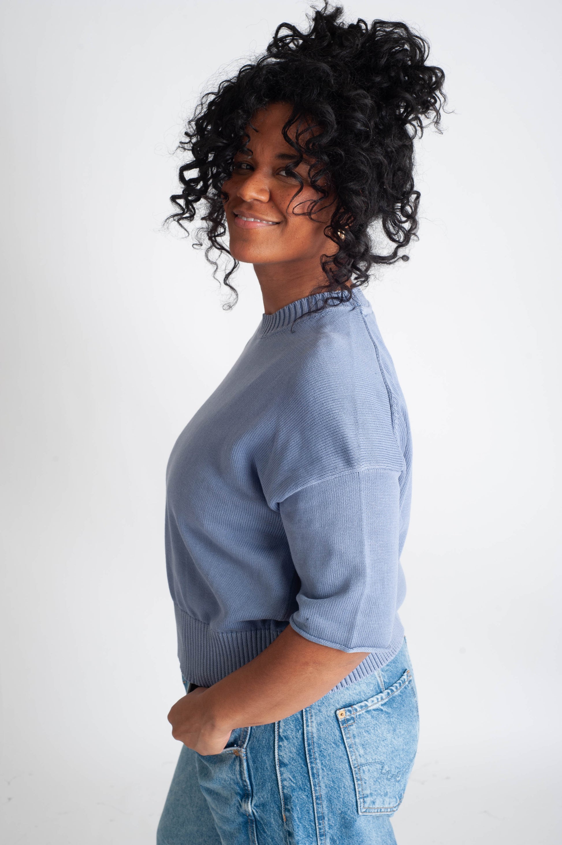 Woman wearing a light blue sweater and jeans on a white background