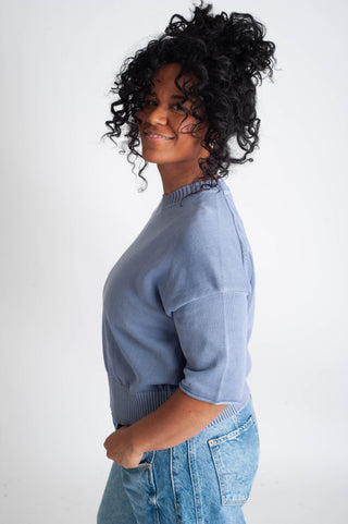 Woman wearing a light blue sweater and jeans on a white background