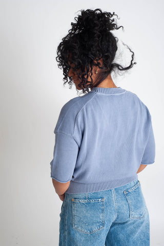 Person wearing a light blue sweater and jeans on a plain background